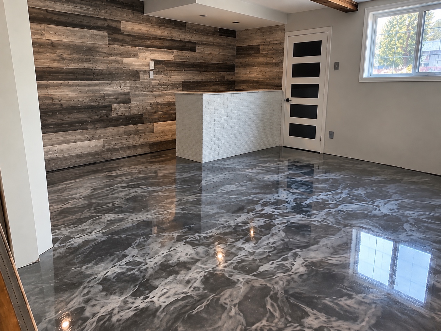Plancher résidentiel en époxy métallique noir et gris brillant devant un mur en bois.